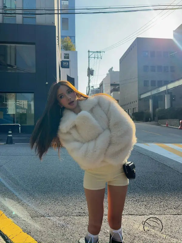 Short loose casual faux fur coat in cream with black trim and pockets by Langry