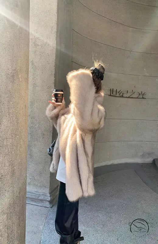Cream-colored faux fur hooded jacket with black leather boots