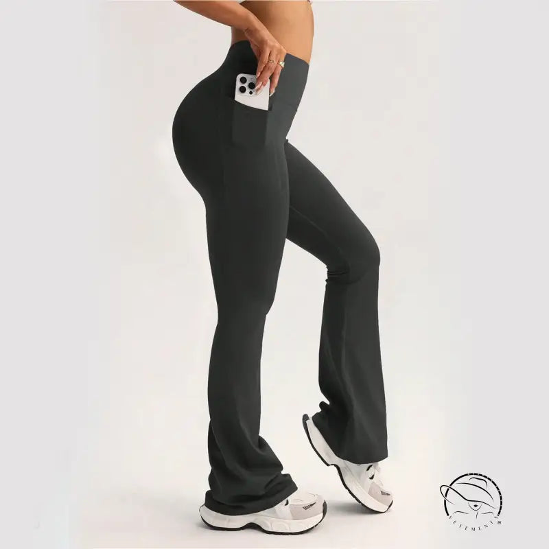Black high-waisted flared langry yoga pants with side pocket holding white smartphone