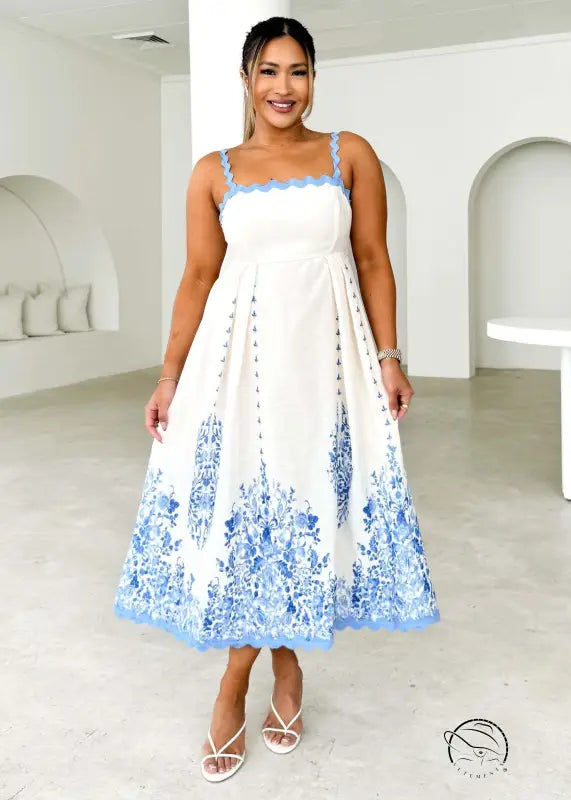 Attractive backless dress in white with blue floral hem and spaghetti straps